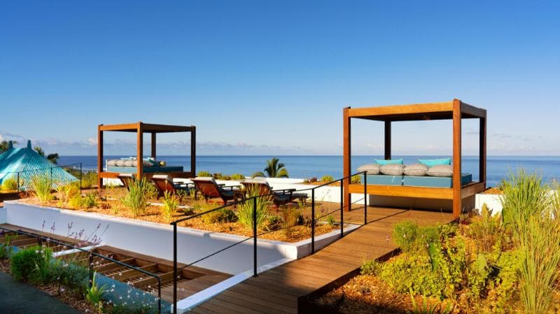 The terrace at Blue Margouillat in Saint-Leu: daybeds under timber pergolas facing the Indian Ocean