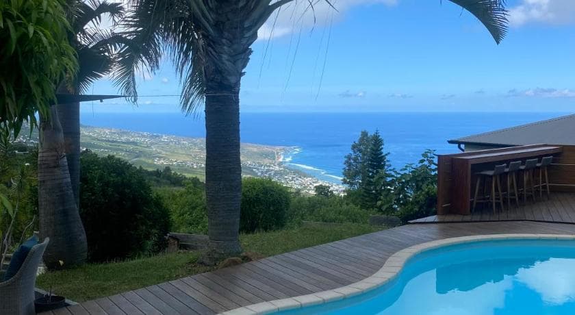 The pool at Kaz Oréa in Les Colimaçons, a timber deck and a view down to the Saint-Leu coast
