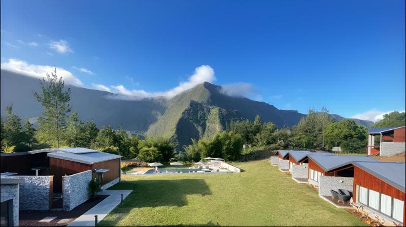 Bungalows du Sarana à Salazie alignés sur une pelouse, piscine au centre et montagnes du cirque sous un ciel bleu
