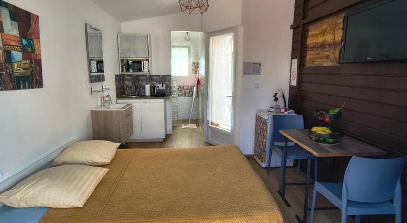Inside the Chez Frida studio: bed, white kitchenette and a small table by the glass door