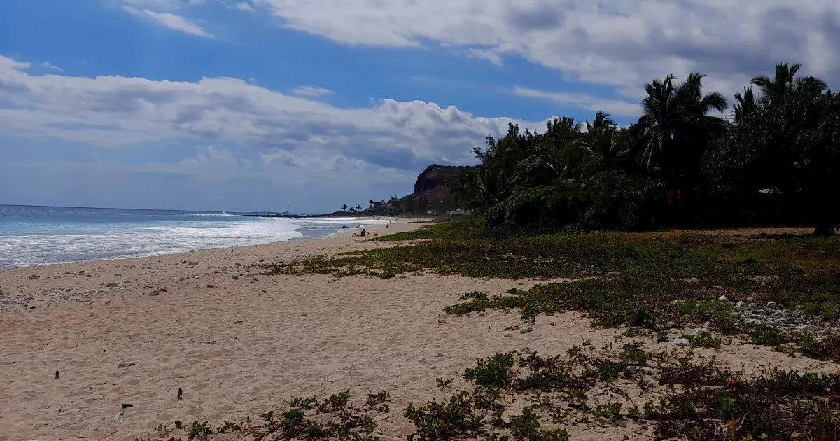 Boucan Canot beach in Reunion Island with golden sand, reef foam and Cap Homard in the background, a typical beachfront wild-camping setting