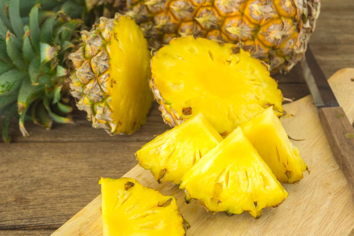 Ananas Victoria entier et tranches dorées sur planche à découper en bois