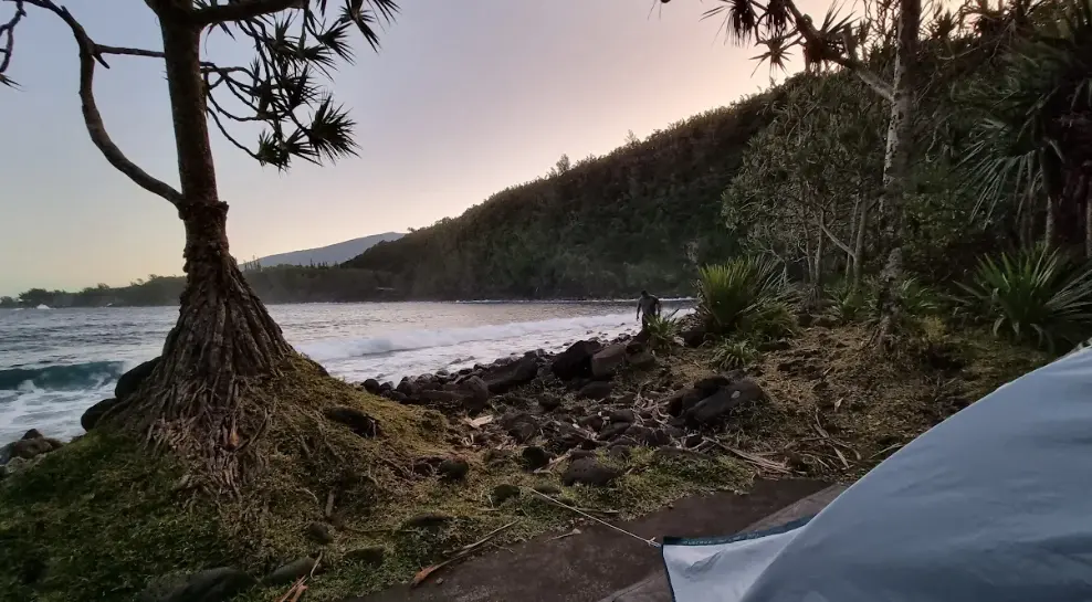 Tente de bivouac à l'Anse des Cascades à Piton Sainte-Rose au lever du soleil avec mer et filaos