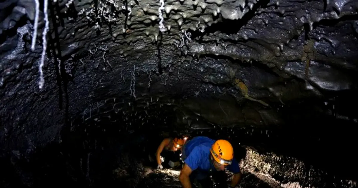 Exploration d'un tunnel de lave du Piton de la Fournaise avec casque et frontale