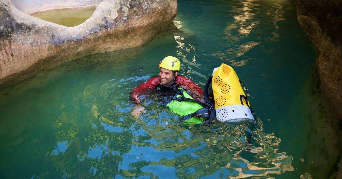 Pratiquant en combinaison et casque pendant une randonnée aquatique sur la rivière Langevin