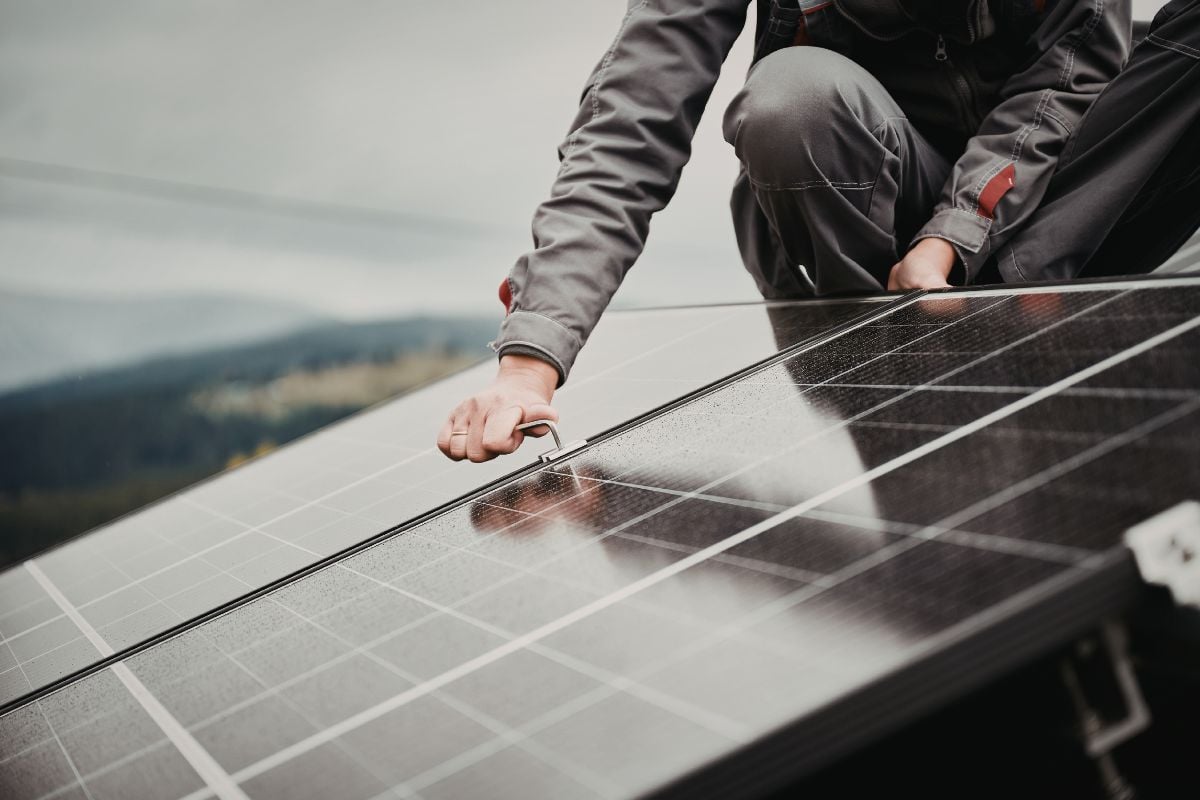 Mains d'un installateur fixant un panneau solaire photovoltaïque sur une toiture