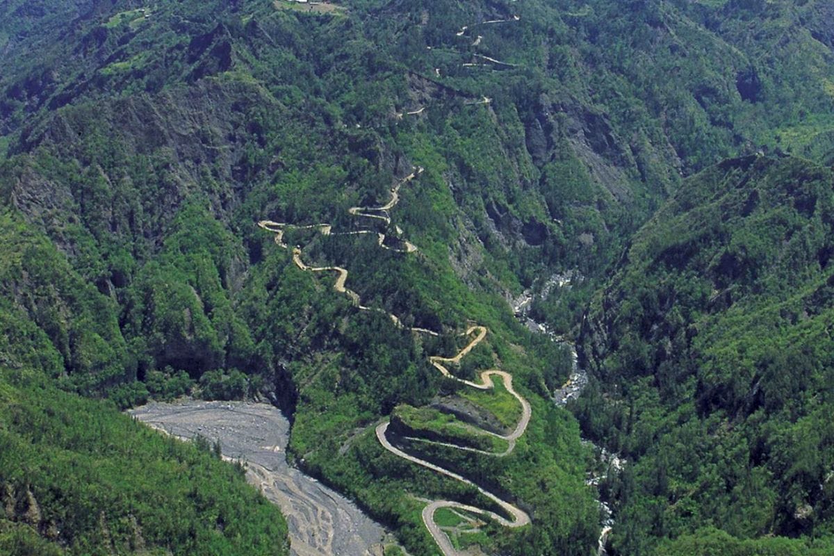 Hairpin bends of the Cilaos road winding through a green valley above a riverbed