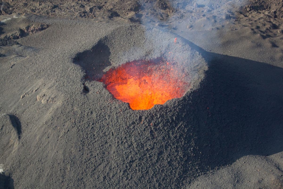 Bouche éruptive du Piton de la Fournaise avec lave incandescente orange au milieu des scories grises
