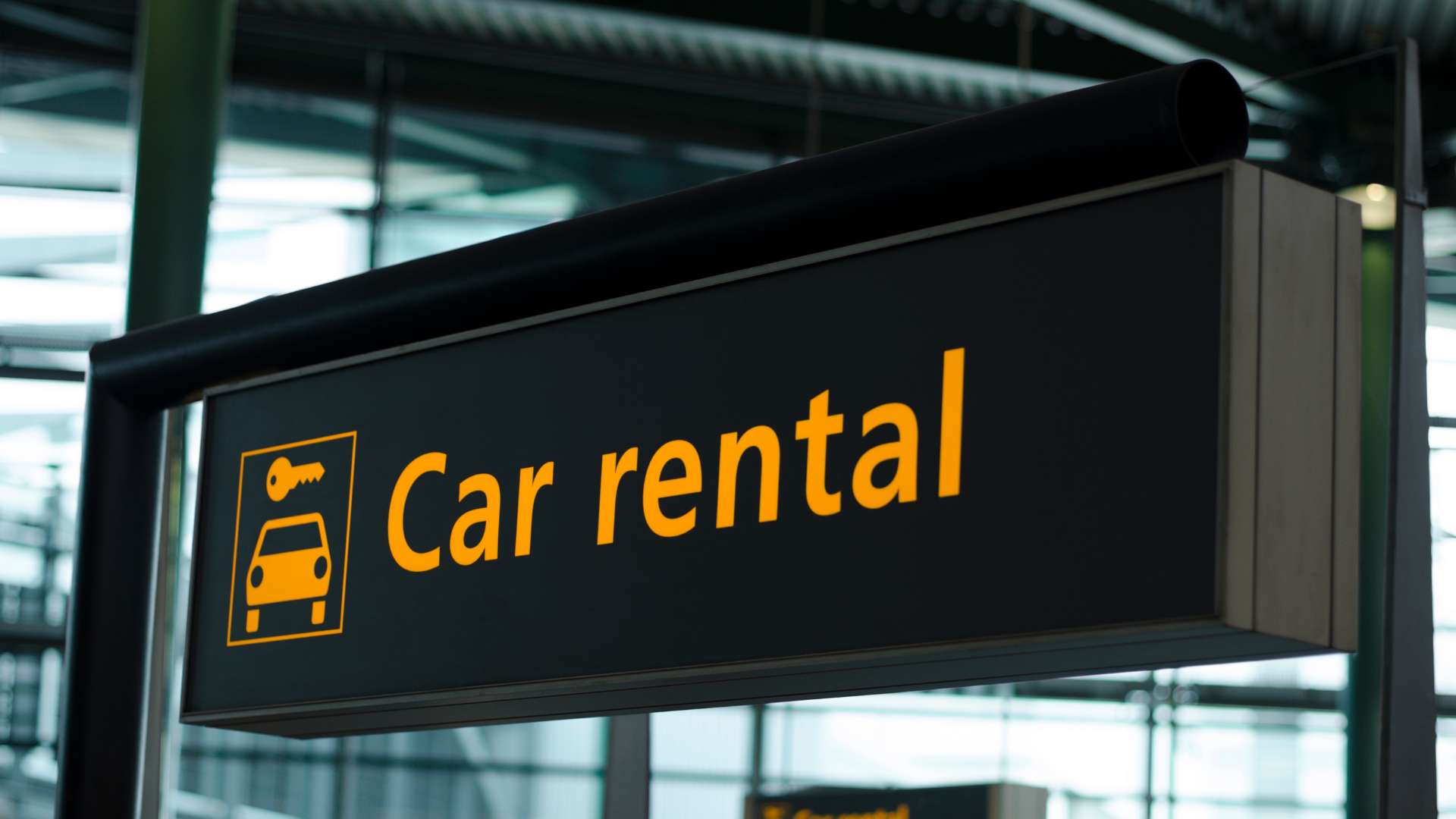 Enseigne Car rental orange et noire dans un hall d'aéroport, comptoir de location de voitures