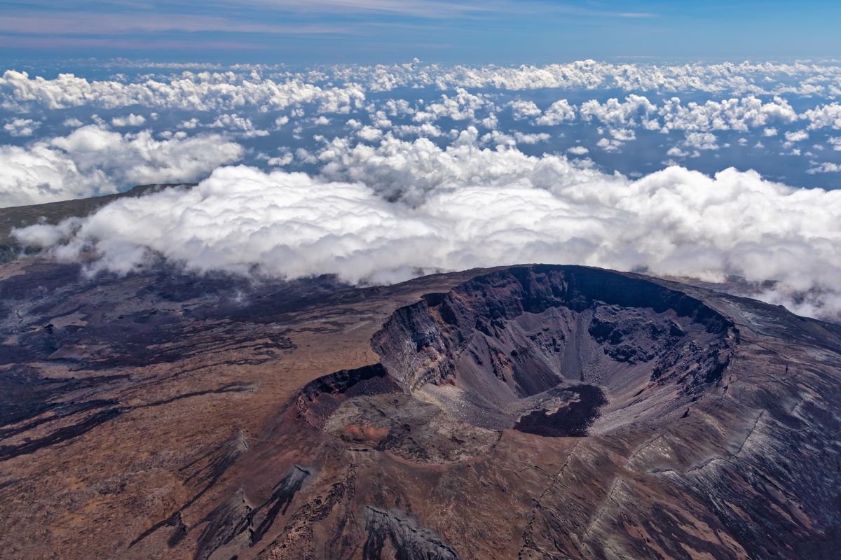 Vue aérienne du cratère Dolomieu du Piton de la Fournaise au-dessus de la mer de nuages, illustrant le territoire physique du département de La Réunion