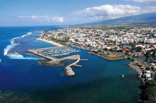 Vue aérienne de Saint-Pierre : port de plaisance, ville étendue, lagon turquoise et premiers contreforts du Tampon en arrière-plan