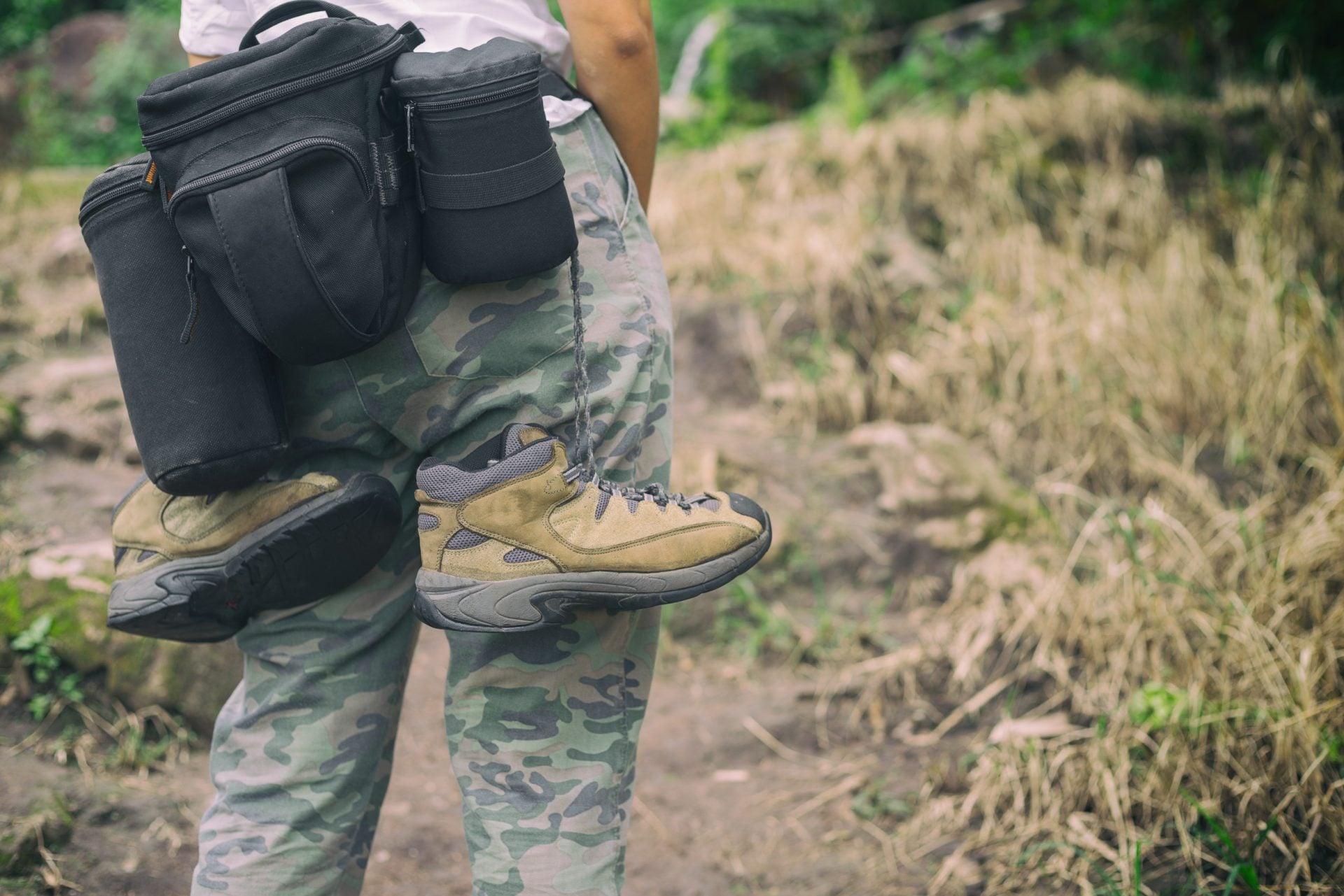 Détail d'équipement randonnée : chaussures de marche, pantalon technique, sacoches portées à la ceinture