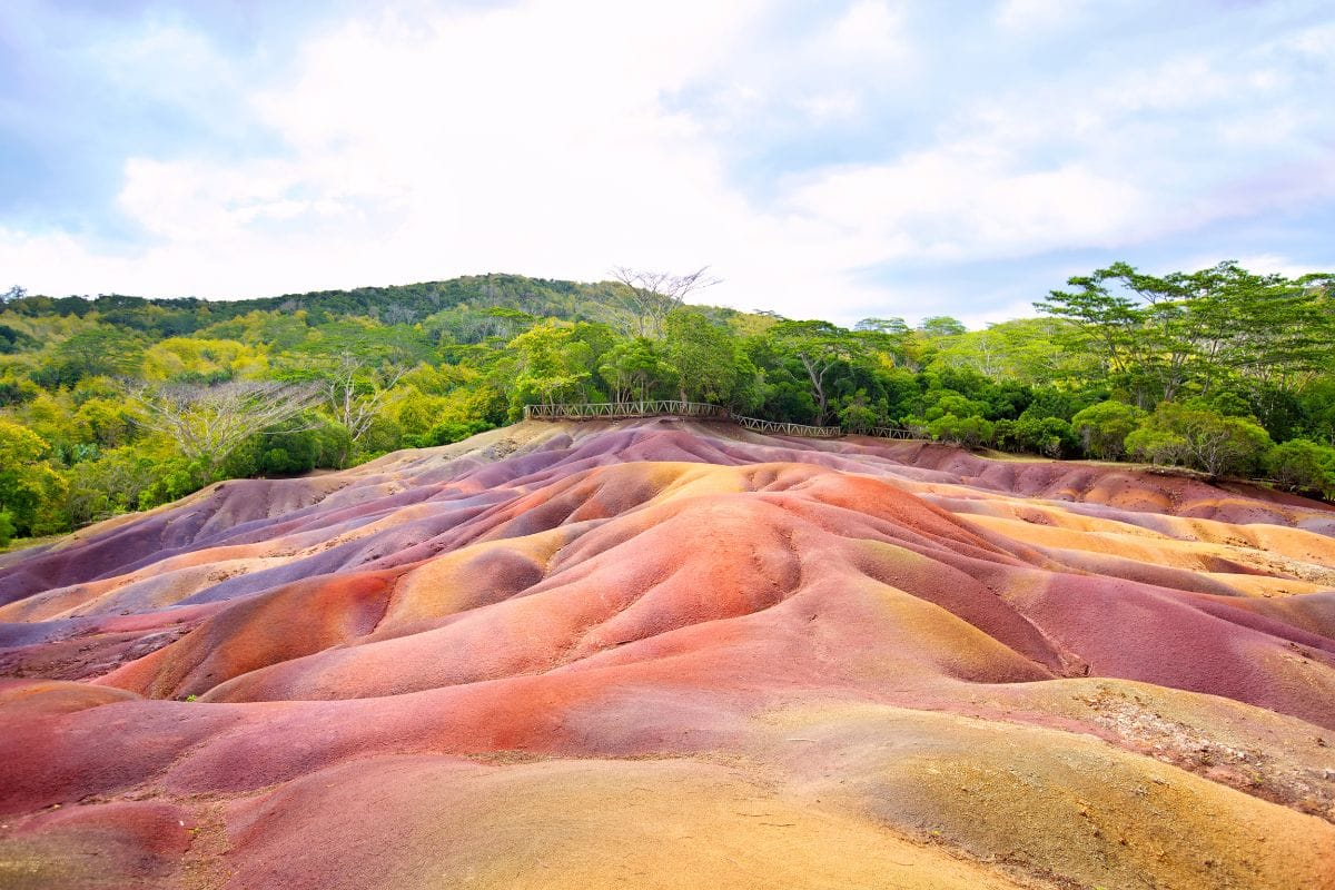 Dunes de terre rouge, ocre et violette de la Terre des Sept Couleurs à Chamarel, forêt en arrière-plan