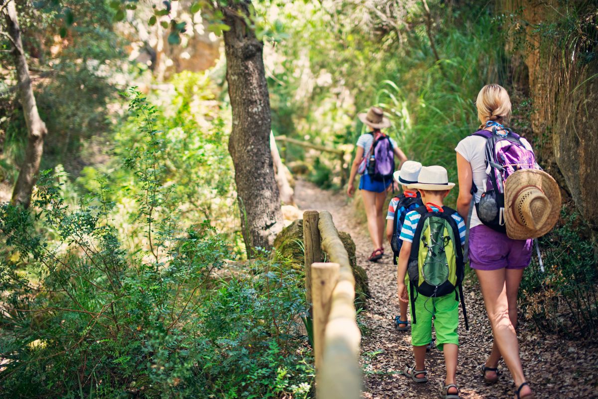 A mother and her son on a family hike on a trail in Reunion Island, backpacks, hats