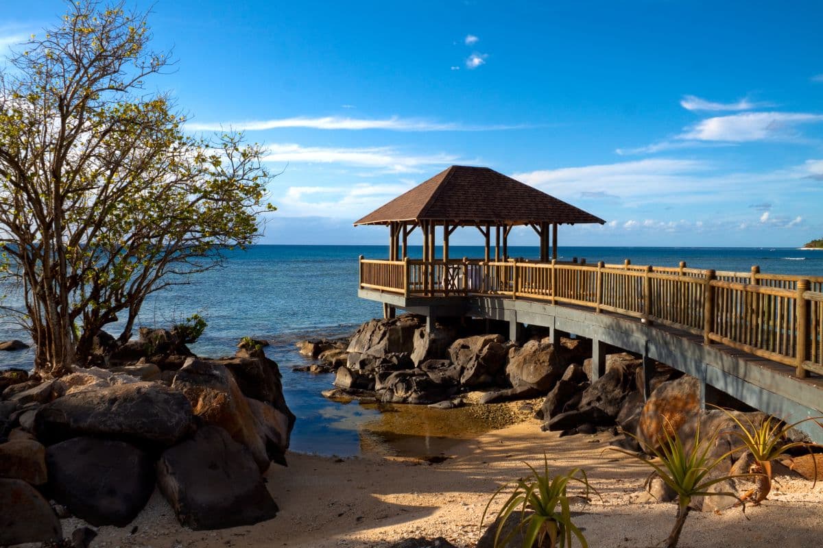 Pavillon en bois au bout d'un ponton, au-dessus d'un rivage de rochers volcaniques et d'une mer calme