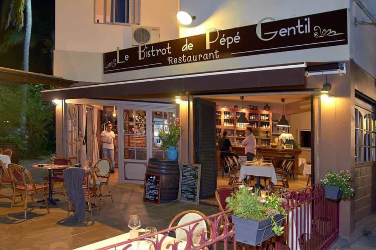 Façade illuminée du Bistrot de Pépé Gentil de nuit, terrasse en bois, sa devanture créole et son bar à vins