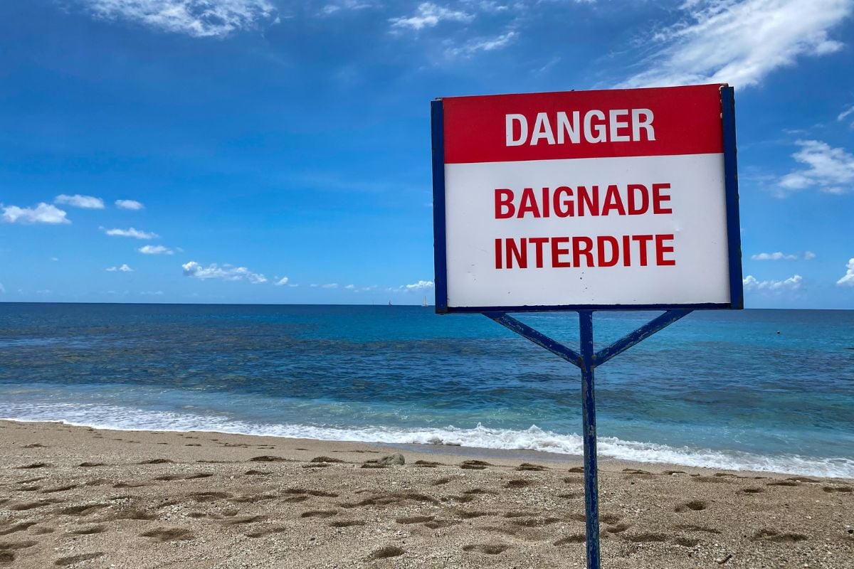 Panneau « Danger Baignade Interdite » planté sur une plage de La Réunion face à l’océan Indien