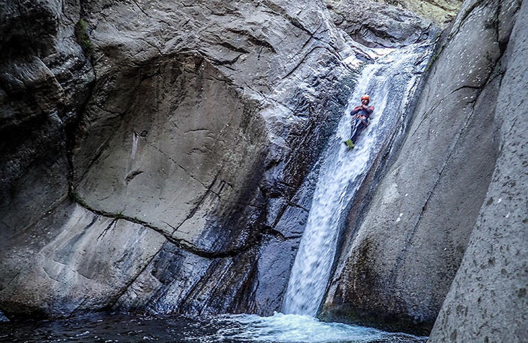 Canyoneur en combinaison rouge sur cascade dans le cirque de Cilaos à La Réunion