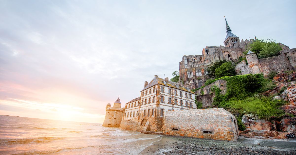 Le Mont Saint-Michel au coucher de soleil, vu depuis la grève à marée basse
