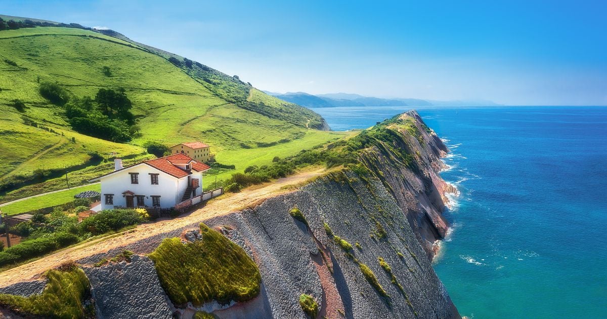 Côte basque avec une maison blanche au toit rouge sur des falaises vertes face à l'océan Atlantique