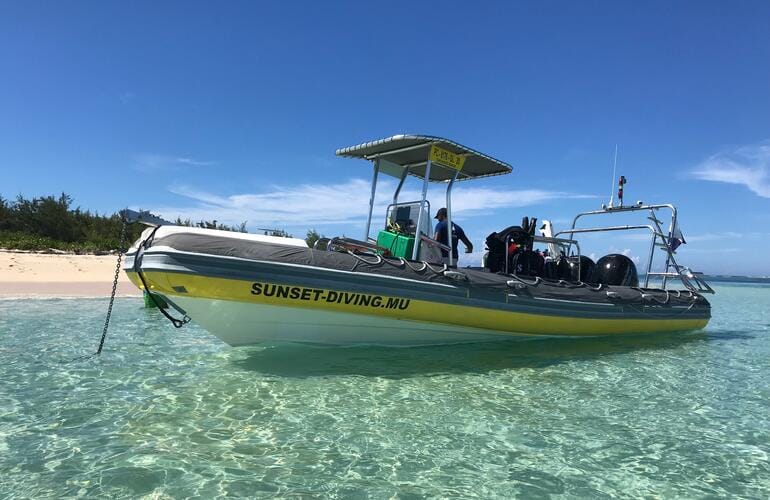 Bateau de plongée au mouillage dans un lagon aux eaux claires, près d'une plage de sable