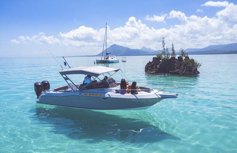 A motorboat anchored near a rocky islet in a turquoise lagoon
