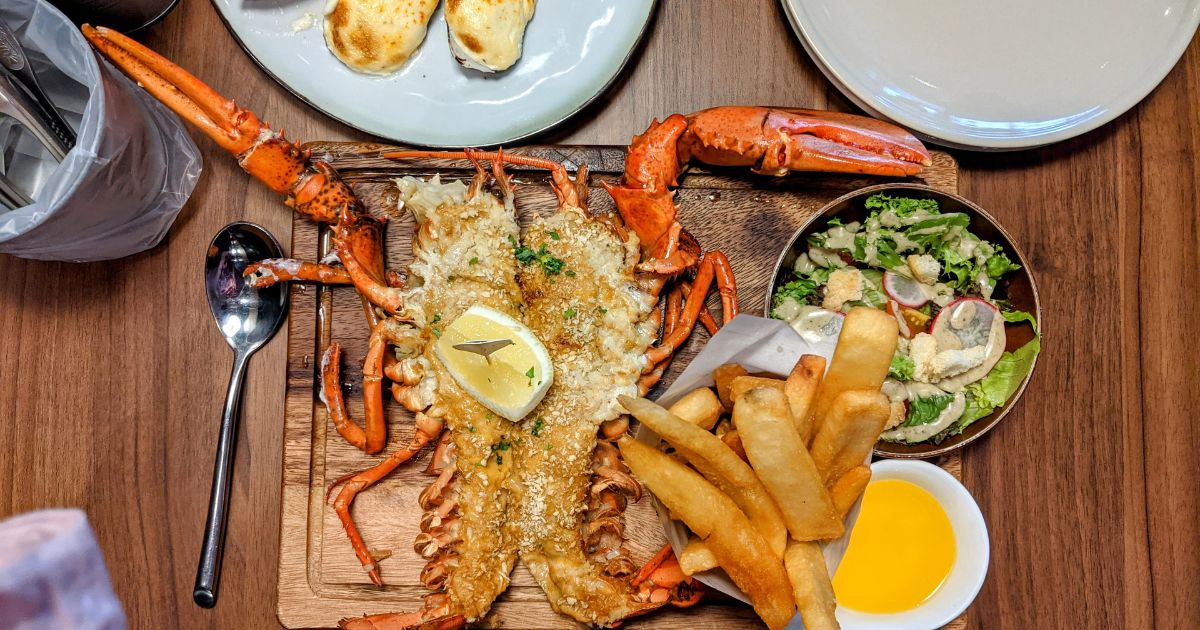 Plateau de homard grillé avec frites et salade verte dans un restaurant de bord de mer à Saint-Gilles