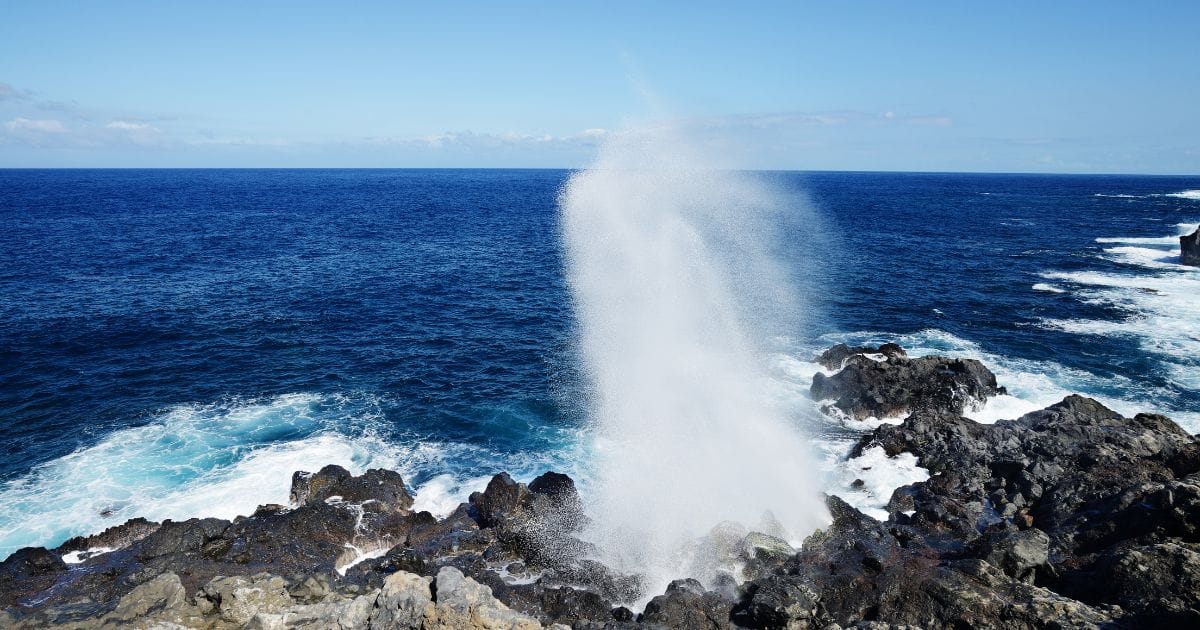 The Saint-Leu Souffleur blowhole shooting spray above basalt rocks