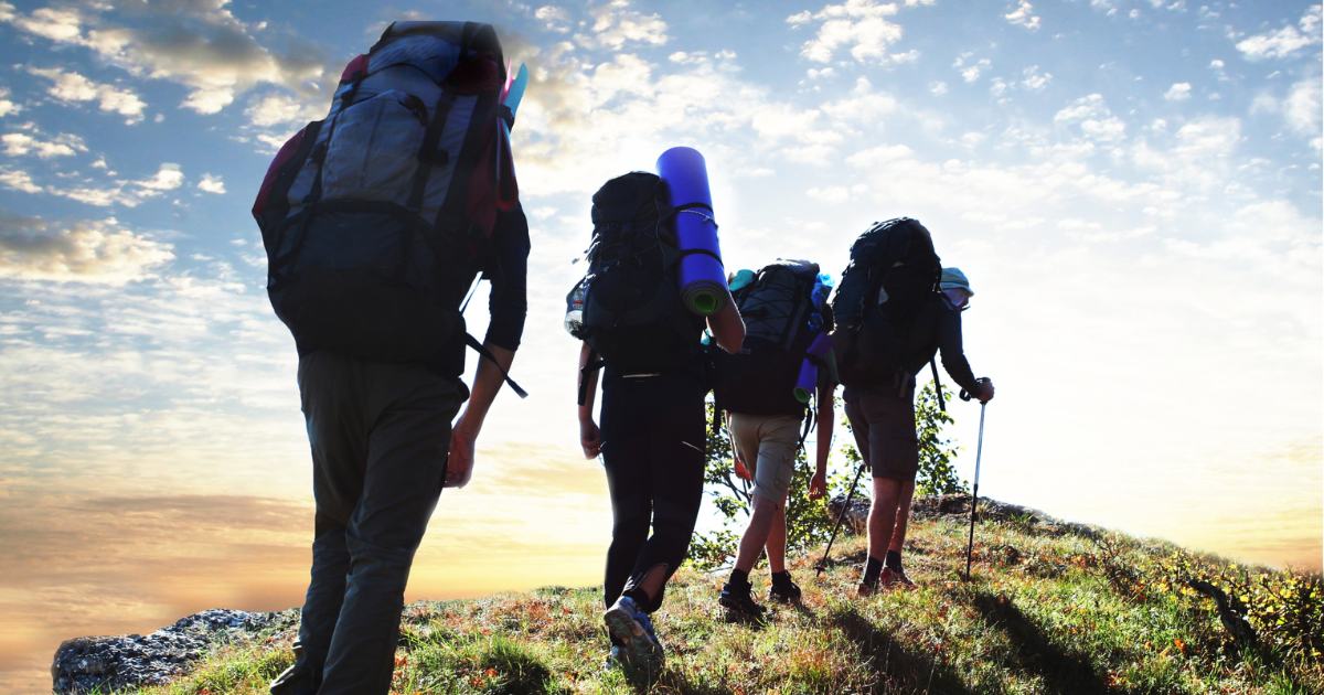 Randonneurs en silhouette au coucher du soleil sur un sentier de La Réunion : la randonnée occupe la moitié du blog conseils voyage