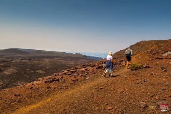 Randonneurs sur la Plaine des Sables, terre rouge martienne, chaîne de montagnes en arrière-plan