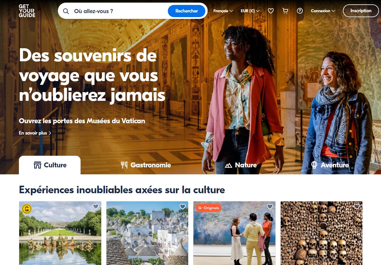 Page d'accueil GetYourGuide avec deux voyageuses souriantes dans la galerie des cartes du Vatican, accroche Des souvenirs de voyage que vous n'oublierez jamais, barre de recherche et navigation Culture, Gastronomie, Nature, Aventure