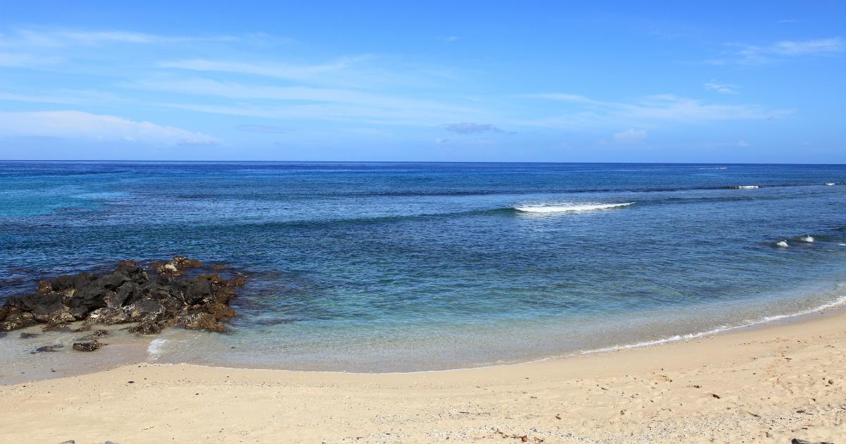 A light-sand beach in Reunion Island in May, a turquoise lagoon, basalt rocks and a pure blue sky as the dry season begins