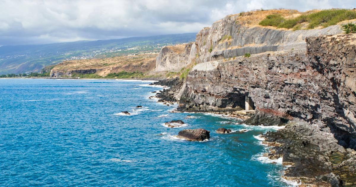 Côte sauvage de La Réunion en saison humide, falaises basaltiques et océan agité sous un ciel chargé