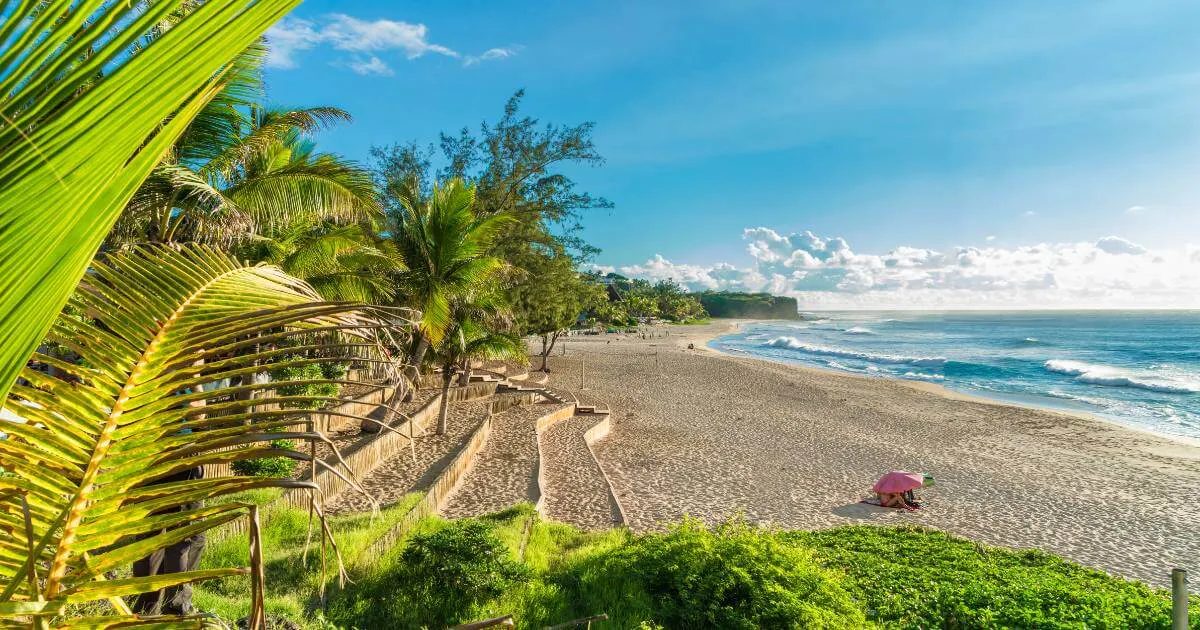 A tropical beach in Reunion Island in November with coconut trees, a turquoise lagoon and blue sky, the return of the austral summer