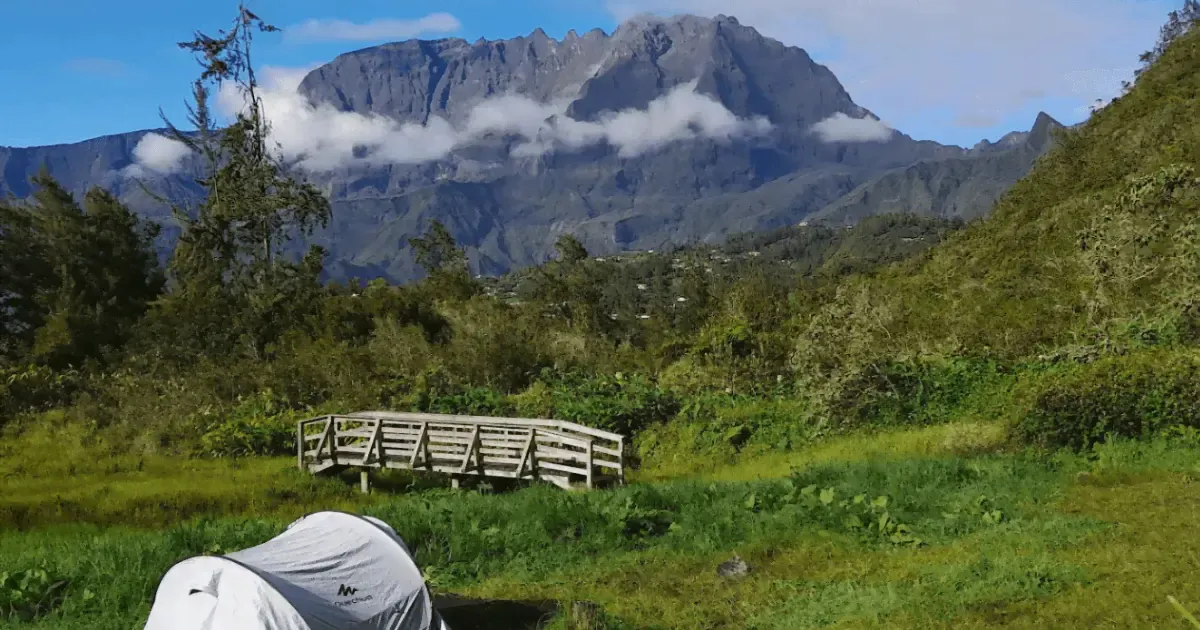 Tente plantée dans une prairie face au massif du Piton des Neiges, aire de bivouac de Ravine Blanche