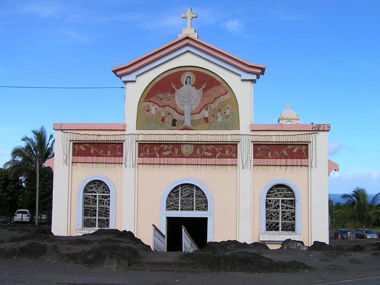 Façade de l'église Notre-Dame des Laves à Piton-Sainte-Rose, fresque du Christ et coulée basaltique de 1977 figée devant l'entrée