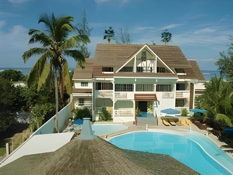 Le Nautile Beachfront at La Saline: gabled building, pool and palm trees with the lagoon behind