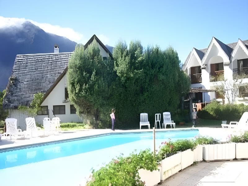 The pool at Le Vieux Cep in Cilaos in front of gabled buildings, with the cirque walls behind