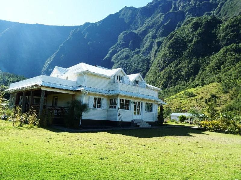 The white Creole house of Chambres d'hôtes Doris in Bras-Sec, lawn and green cirque mountains