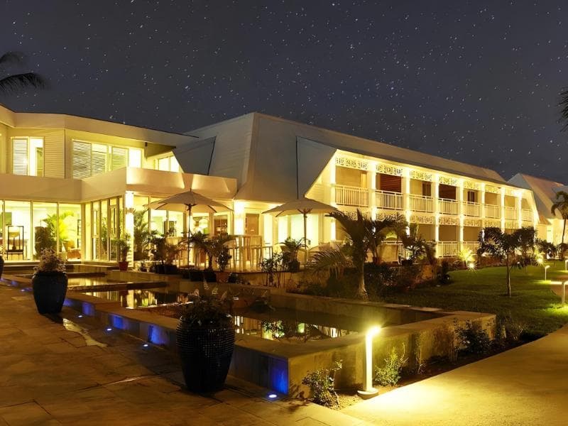 Villa Delisle à Saint-Pierre de nuit : bâtiments blancs illuminés, bassin et jardin tropical sous un ciel étoilé