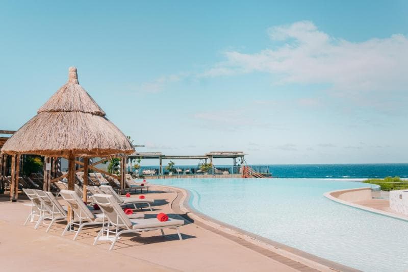 The Akoya's infinity pool at La Saline: sunloungers, a thatched hut and the ocean on the horizon