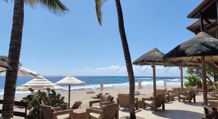 The Saint Alexis beach area at Boucan Canot: armchairs, thatched parasols and palm trees facing the ocean