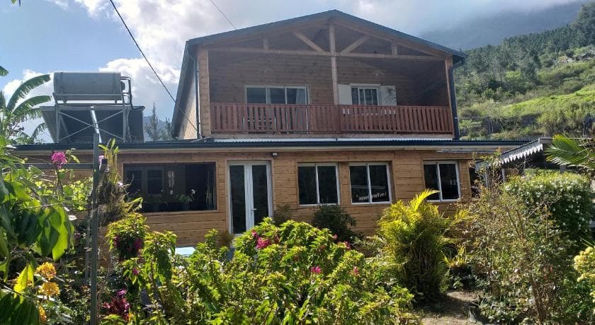 The timber house of Les Amoureux du Cirque guesthouse in Cilaos, with a flower garden in front