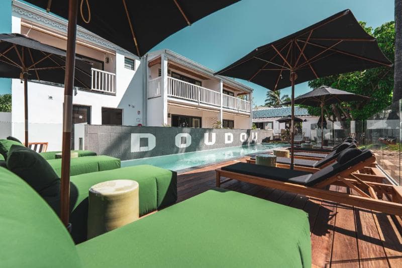 The Doudou Hôtel pool at La Saline with the hotel's name in giant letters, green sunloungers and parasols