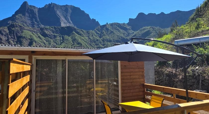 The timber terrace at Les Portes du Taïbit with a parasol, facing the ridges of the Cilaos cirque