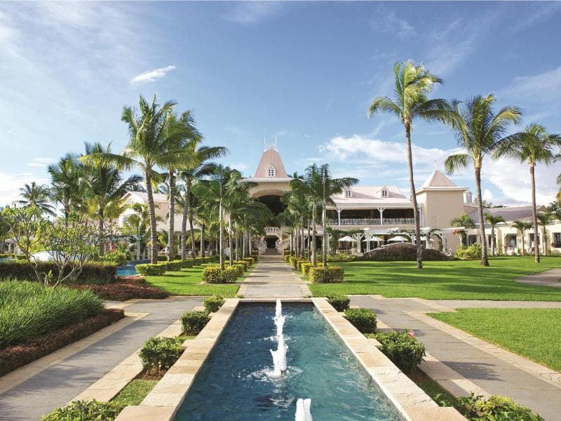 Allée du Sugar Beach menant au manoir colonial, bassin à jets d'eau, pelouses et cocotiers