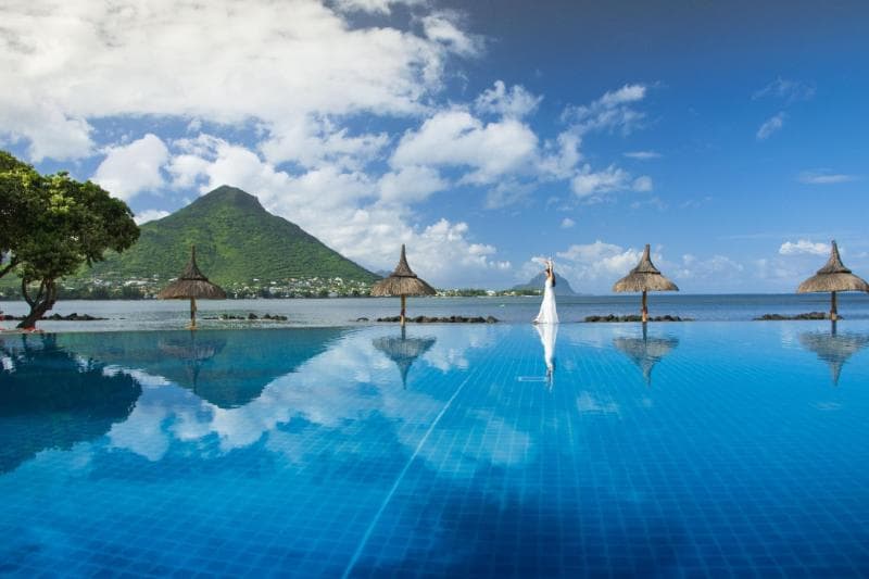 Piscine à débordement du Sands Suites, parasols de chaume et montagne de l'autre côté de la baie