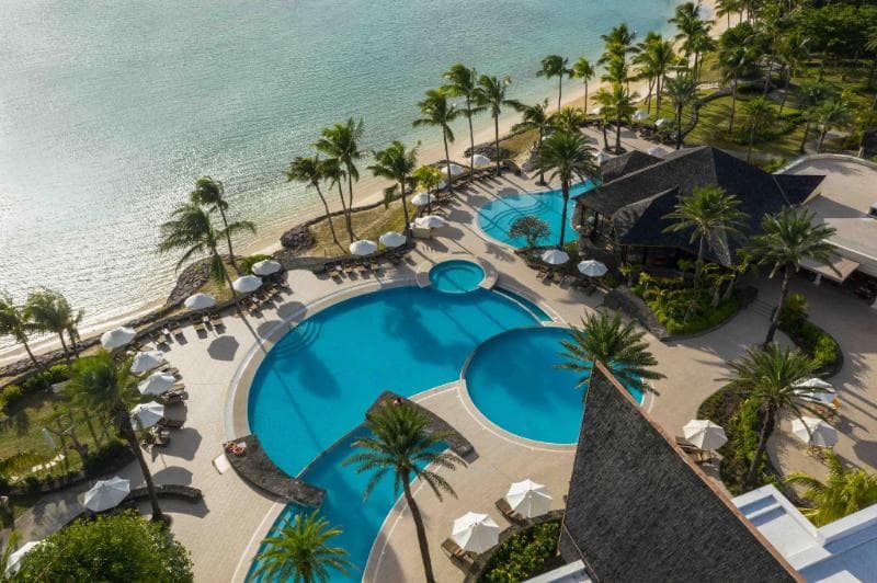 The Residence vu du ciel : piscines en cercles imbriqués entre les palmiers, toit de chaume et plage