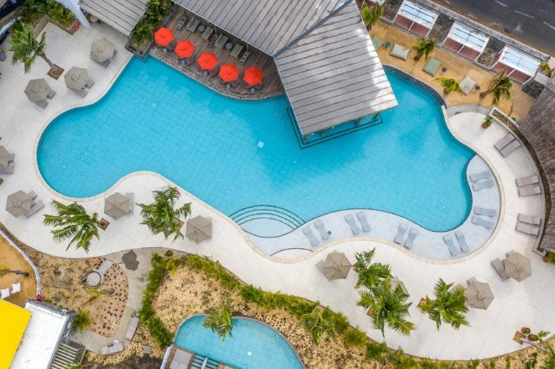 Sunrise Attitude vu du ciel : grande piscine sinueuse, parasols rouges et transats