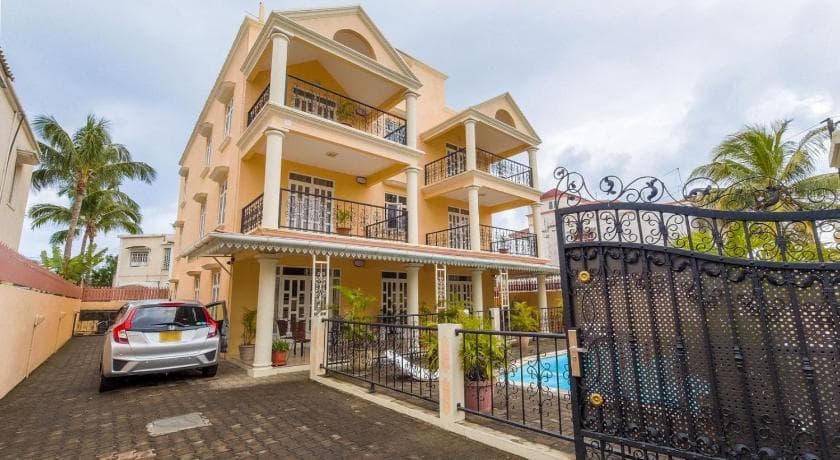 Résidence Le Palmier: an ochre building with balconies behind a wrought-iron gate, the pool just visible